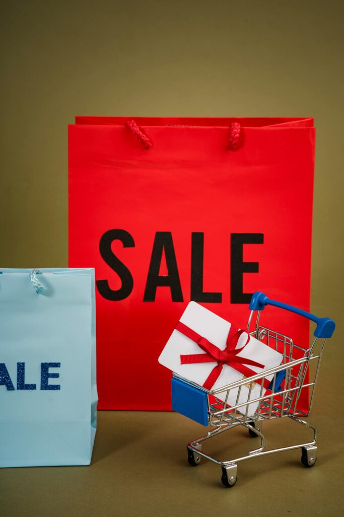 Red and blue shopping bags with a mini cart convey a sale theme.